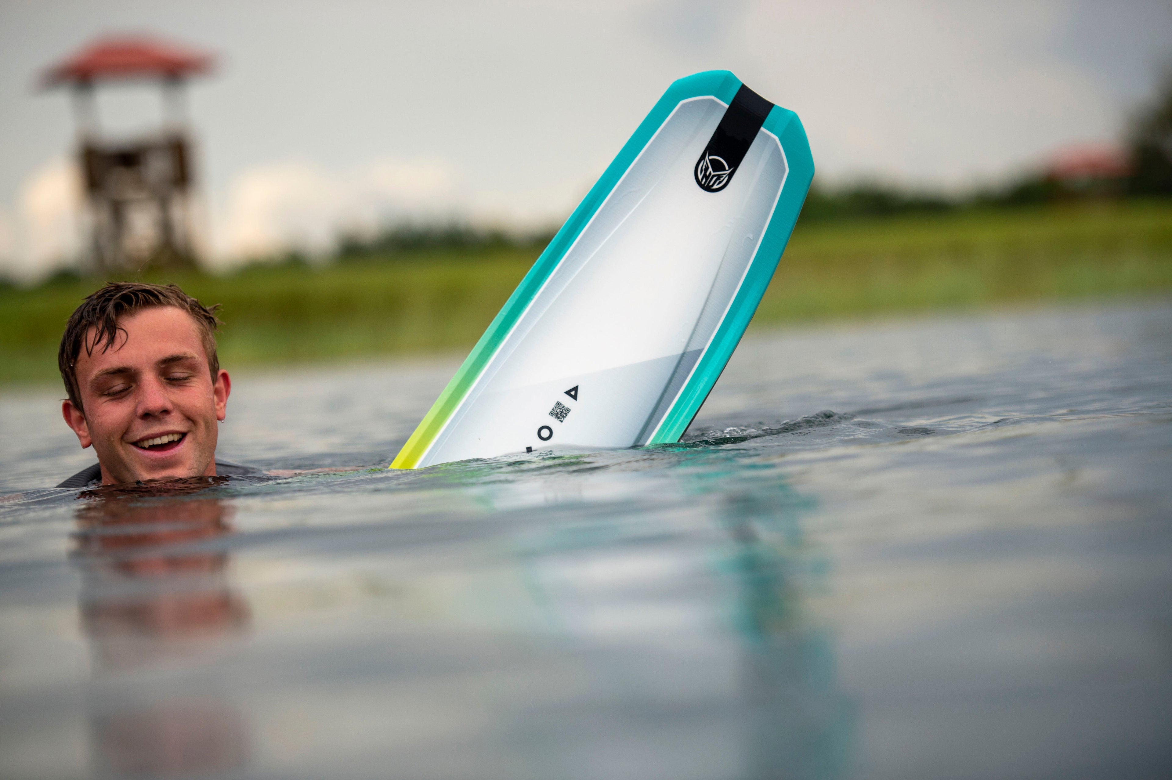 Waterskier submerged in the water wearing a HO Sports life vest and part of his water ski poking out of the water. The waterski is White with Blue and Yellow edges.