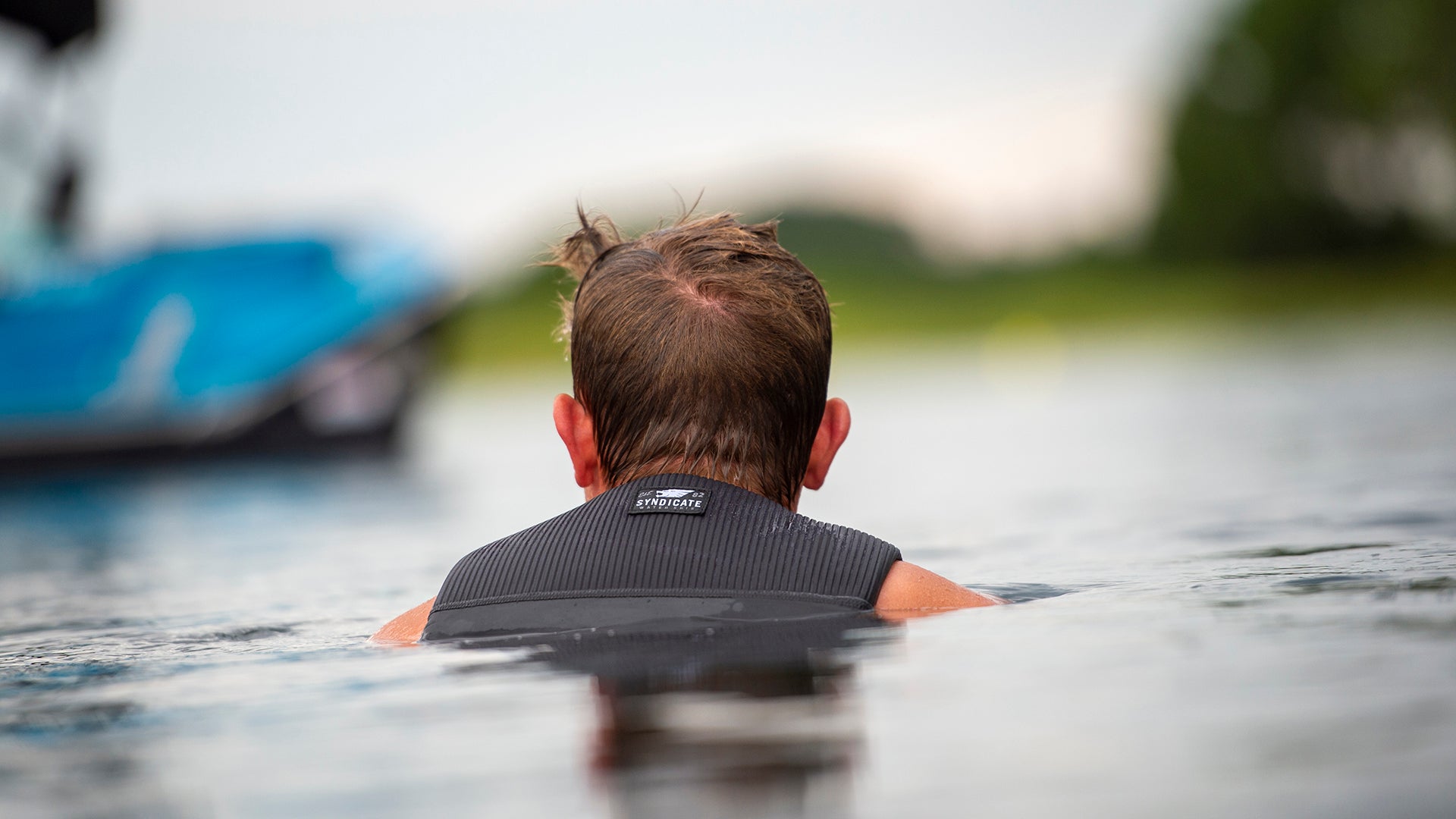 View of a water skier floating in the water with shoulders and the back of his HO Sports Life Vest showing above water.