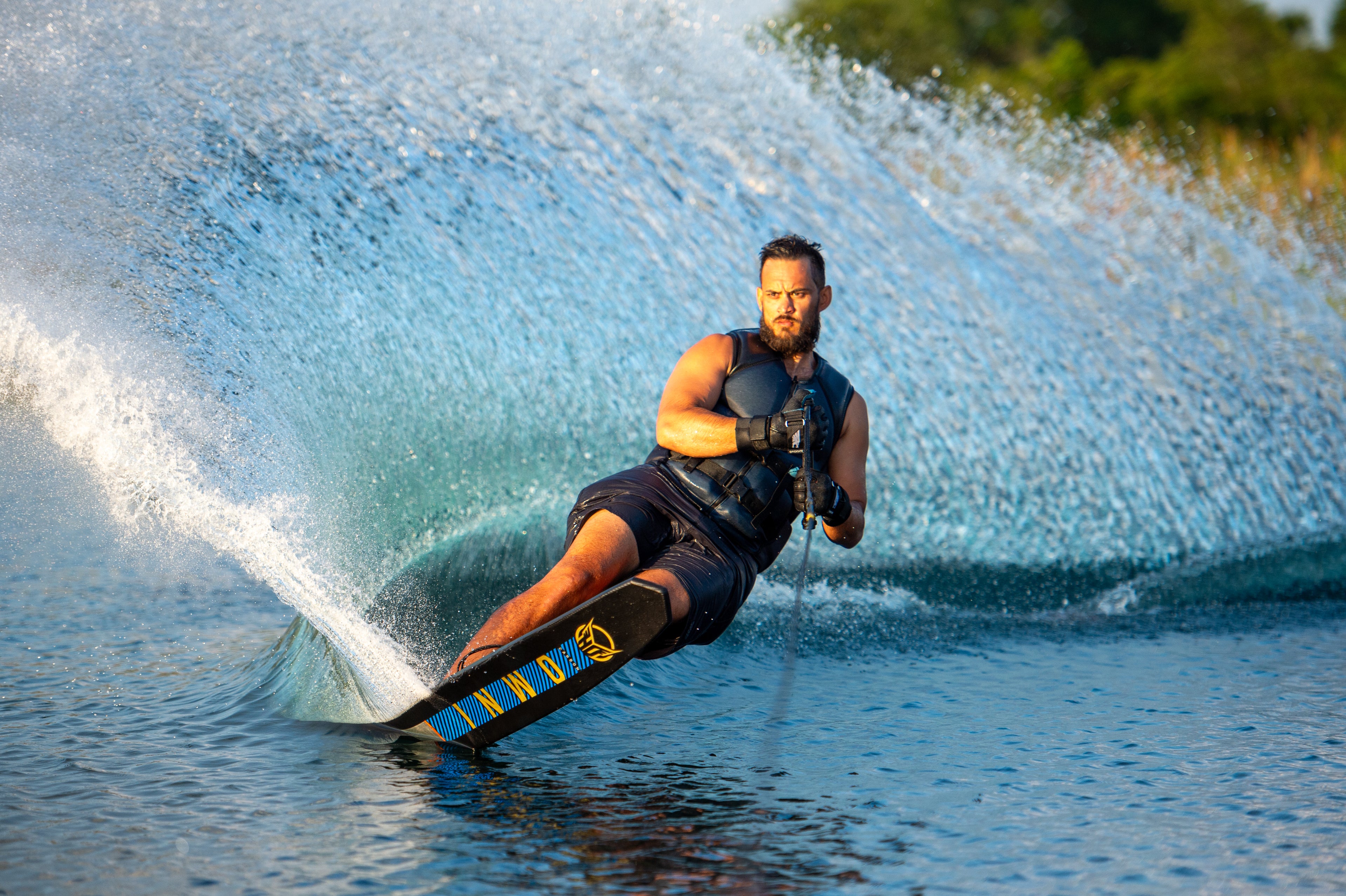 Jon Travers on an OMNI slalom ski, looking focused as he glides across the water.