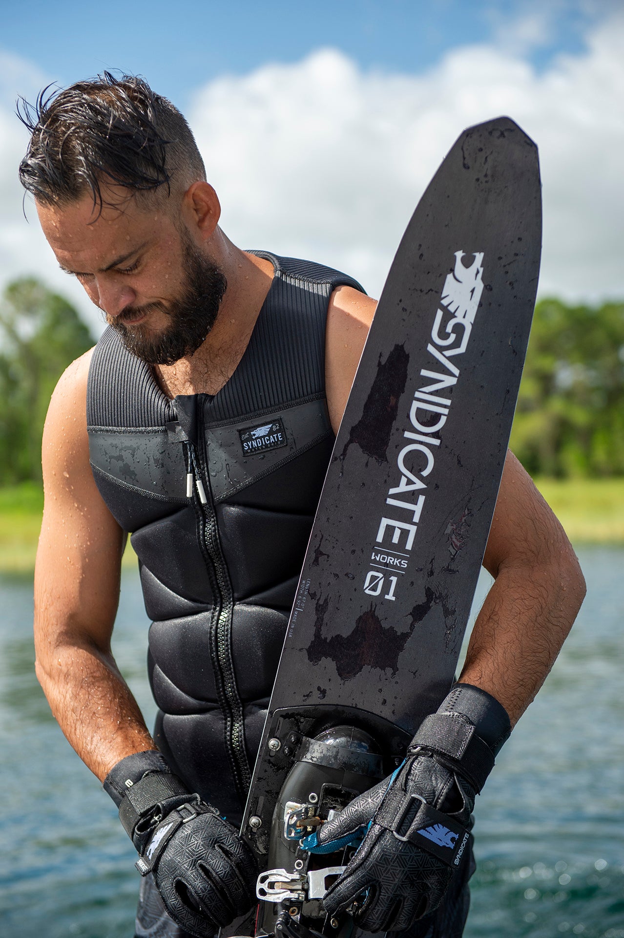 Close-up of man in black vest looking down while holding a Syndicate Works 01 ski.