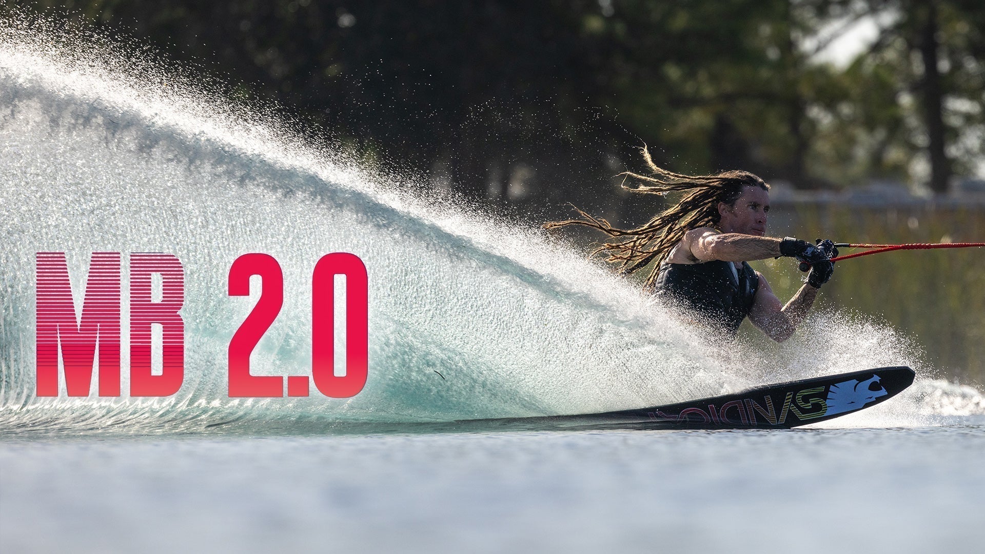 Waterskier carving a spray turn with “MB 2.0” text overlaid on the left side of the image.