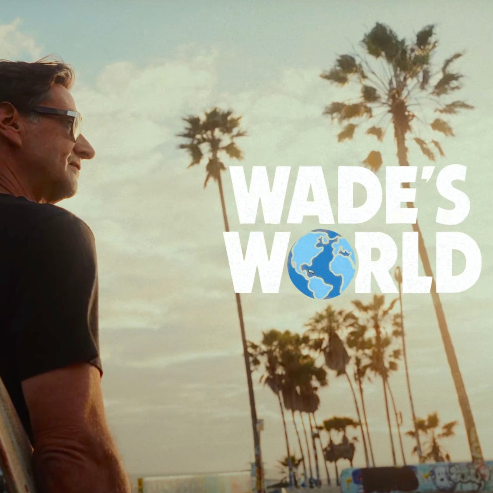Man looks toward palm trees at sunset with “Wade’s World” text and globe graphic overlaid.