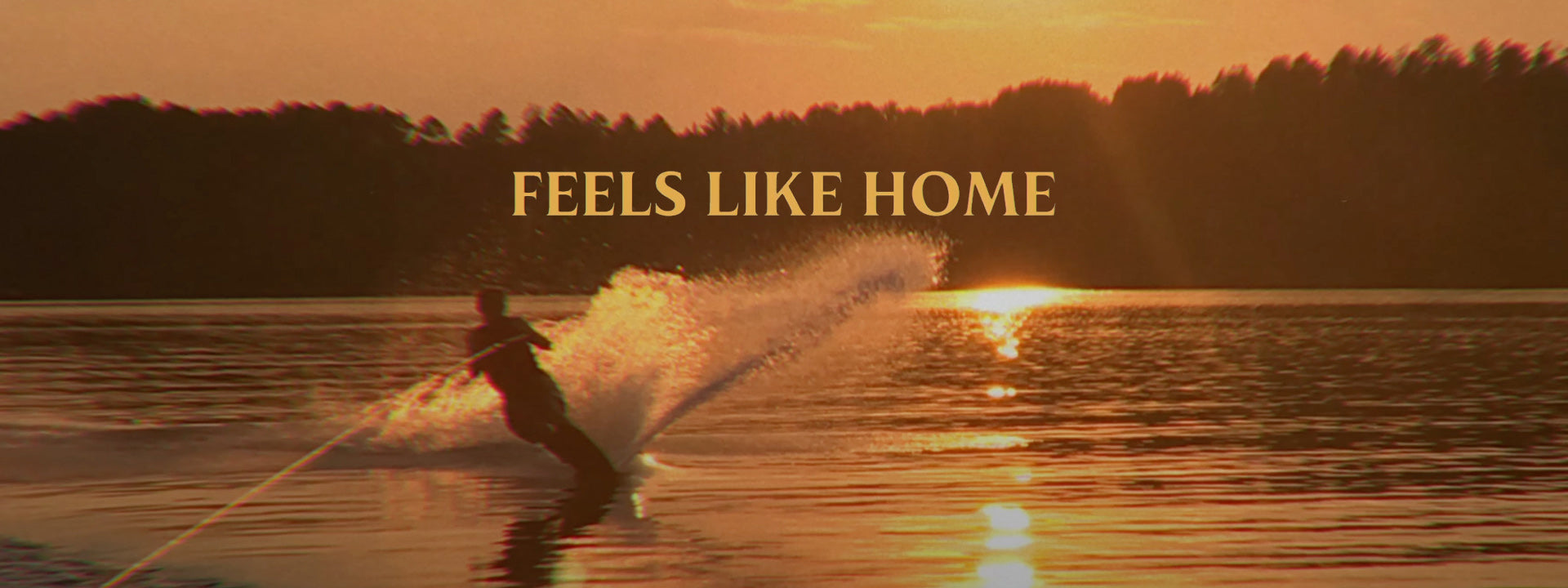 Person water skiing on a lake with a sunset and 'Feels Like Home' text overlay.