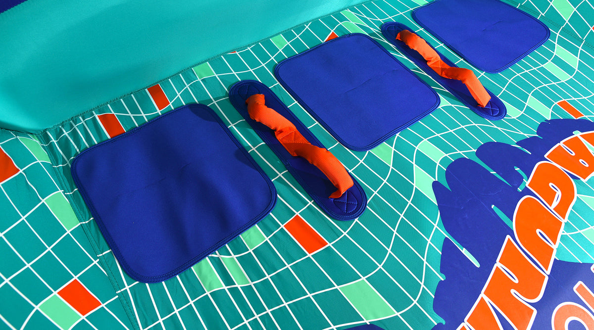 Close-up of blue seat panels and orange grab handles on the teal grid-patterned deck.