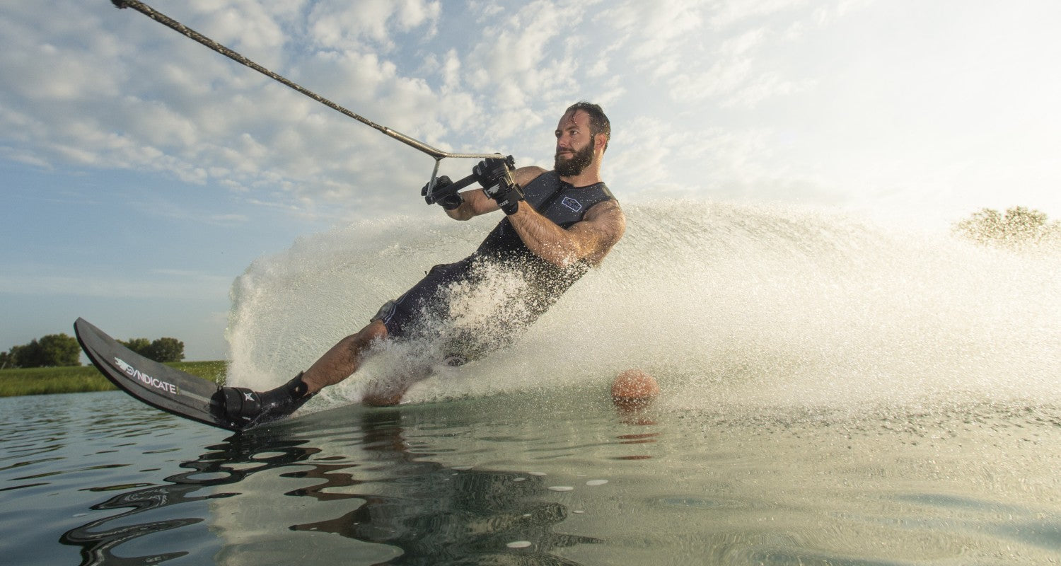 Matteo Luzzeri aggressively leaning into a turn while waterskiing, creating a dramatic water spray.
