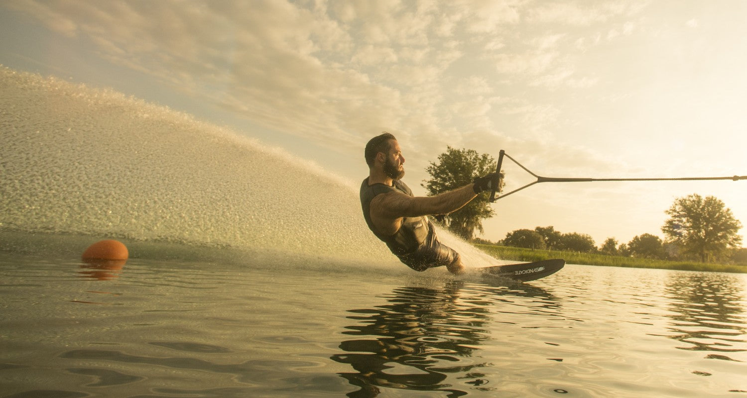 Matteo Luzzeri waterskiing at sunset, carving through the water while holding the handle of the tow rope.