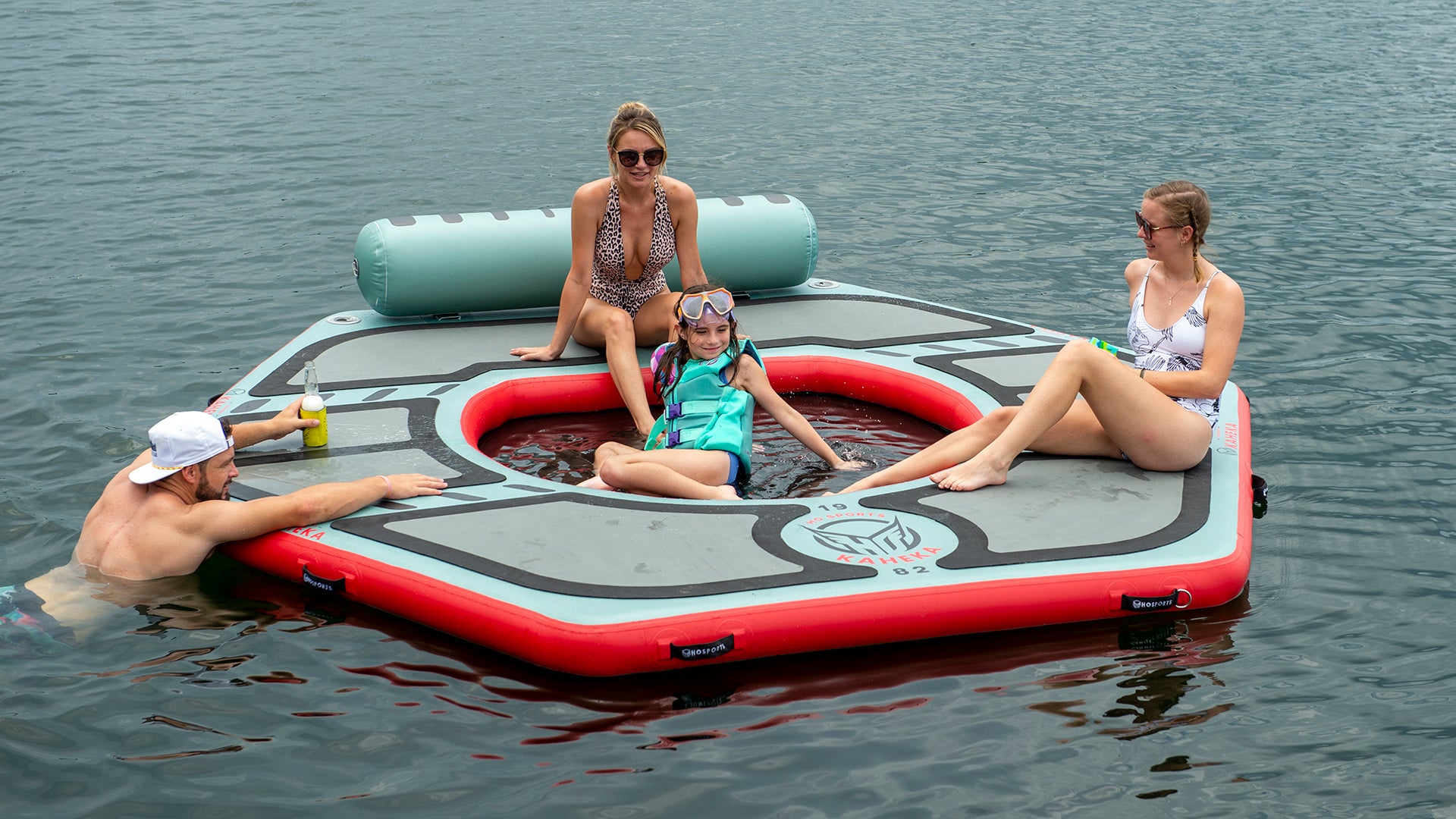 Group of people lounging on an inflatable HO Sports Kaheka float with a sunken seating area in a lake.