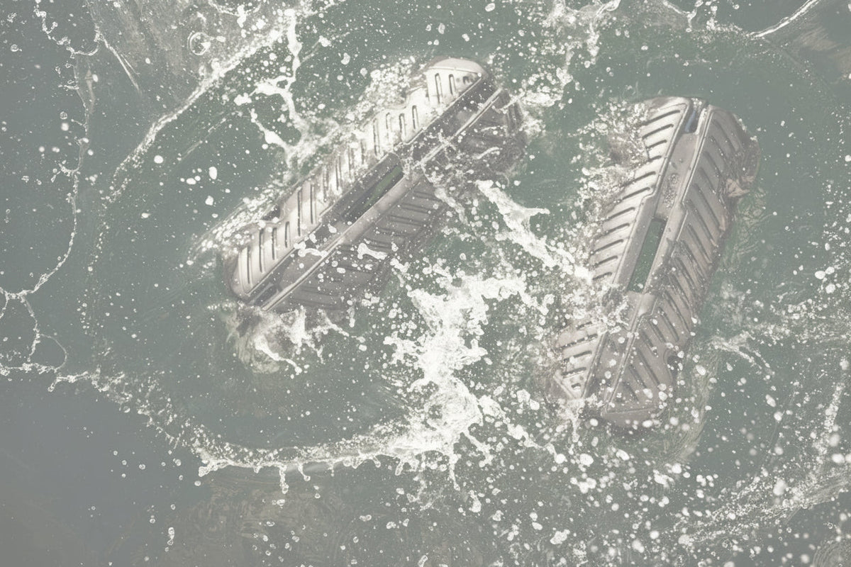 Two black inflatable fenders splashing in the water beside a boat.
