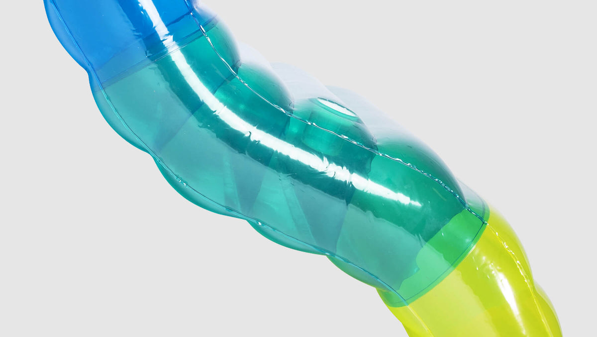 Close-up of Chaise Multi-Lounger's transparent inflatable bolster in blue, teal, and yellow-green gradient.