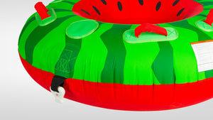 Angled view of Watermelon Tube's green and red surface with red handles, tow strap connector, and warning label.