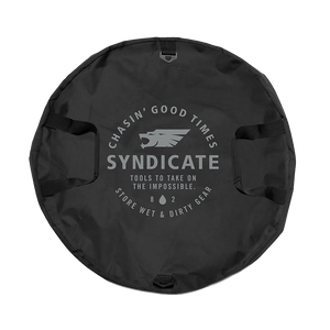 Top view of the black Syndicate Cinch Changing Mat, featuring a circular design, reinforced handles, and bold white logo.