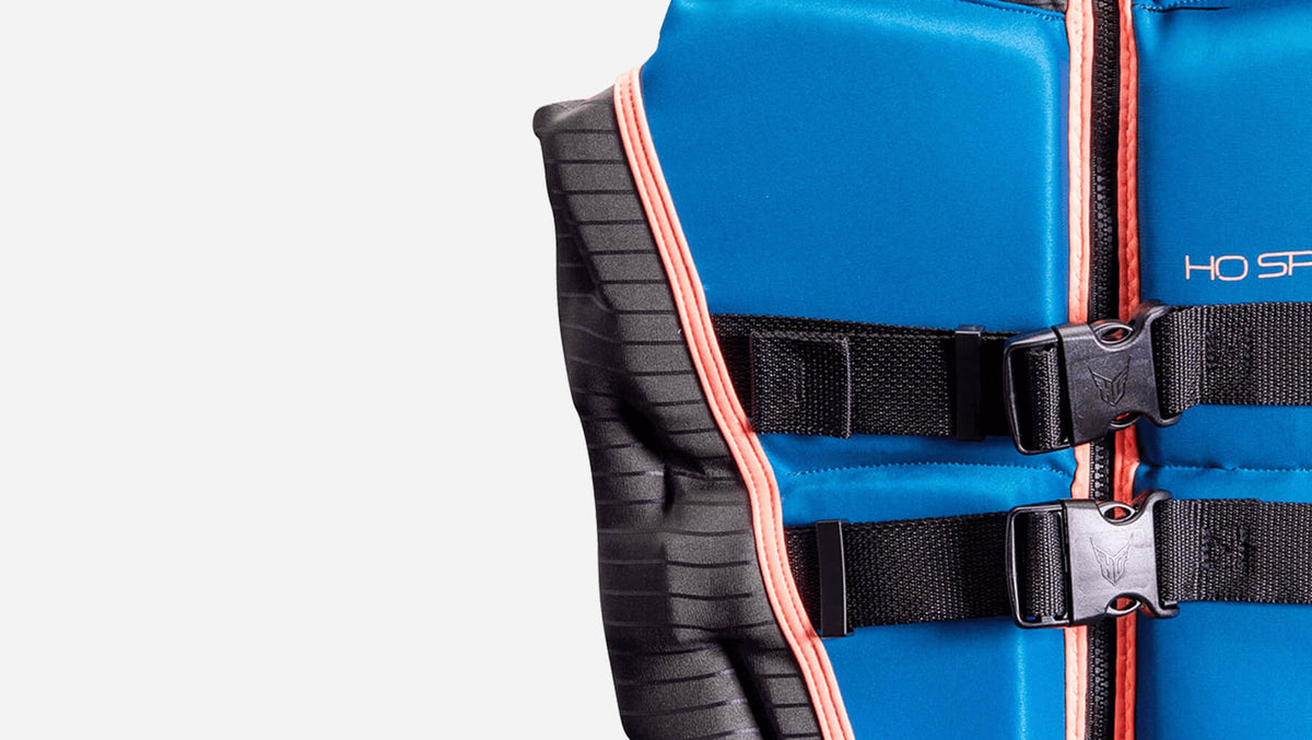 Angled close-up of Womens System vest with black buckles, blue panels, and coral trim.